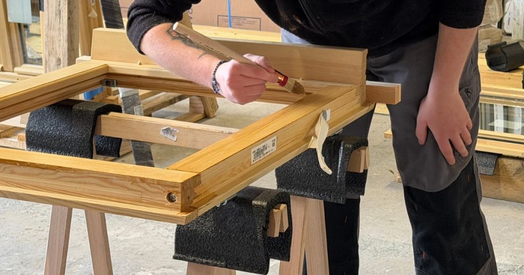 Artisan menuisier Kalio Menuiserie posant une fenêtre bois sur mesure dans une maison ancienne à Vitré