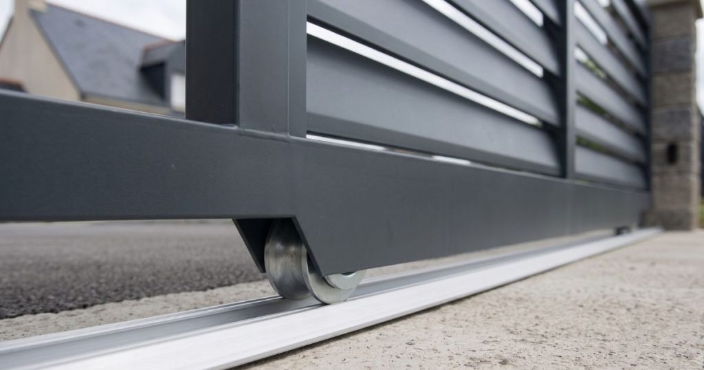 Double galet nylon d’un portail coulissant engagé sur son rail au sol