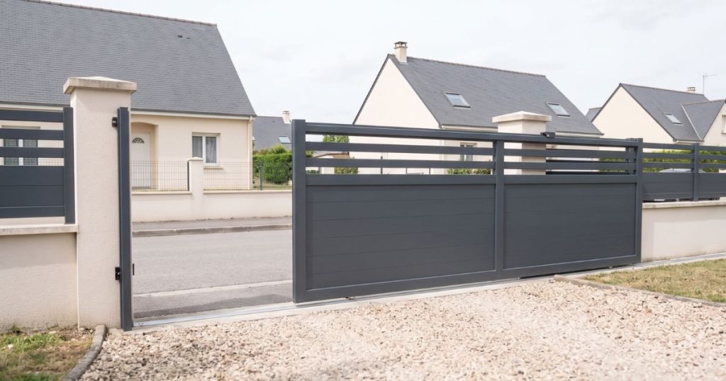 Portail coulissant aluminium Kalio Menuiserie arrêté à mi-course, l’ouverture partielle visible depuis l’allée