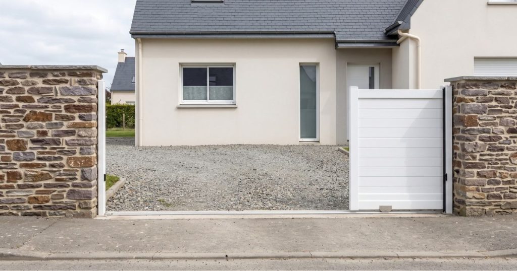 Portail coulissant blanc ouvert à Saint-Jacques-de-la-Lande, tablier effacé le long de la clôture sur sa zone de refoulement