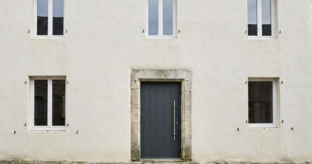 Façade de maison de bourg en schiste avec fenêtres, porte d’entrée et volets battants neufs - visuel Kalio Menuiserie